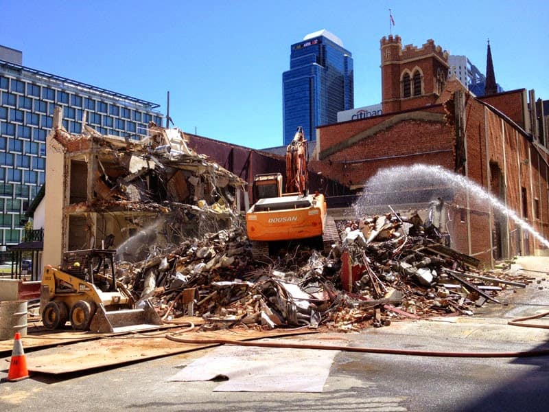 Brajkovich Demolition & Salvage excavator doing demolition in the building with debris piling up